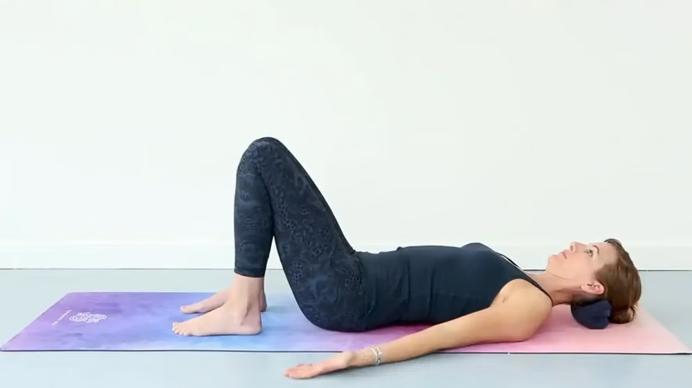 Woman lying on a mat with knees bent, practicing the Core Breath